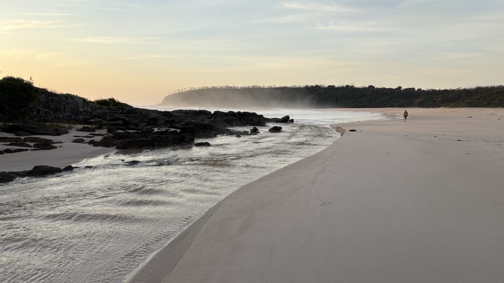 A river flows into a beach at sunrise